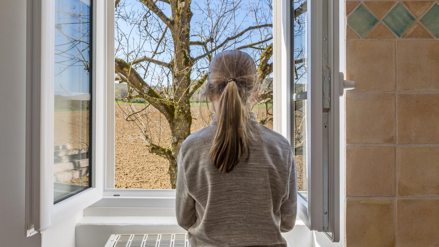 Petite fille devant une fenêtre ouverte